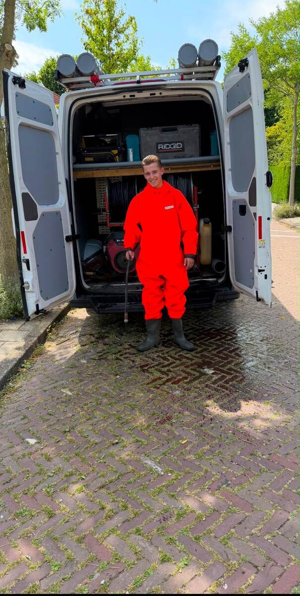 Monteur in werkoverall bij de open bus van Rioolspecialist Hoofddorp met ontstoppingsapparatuur