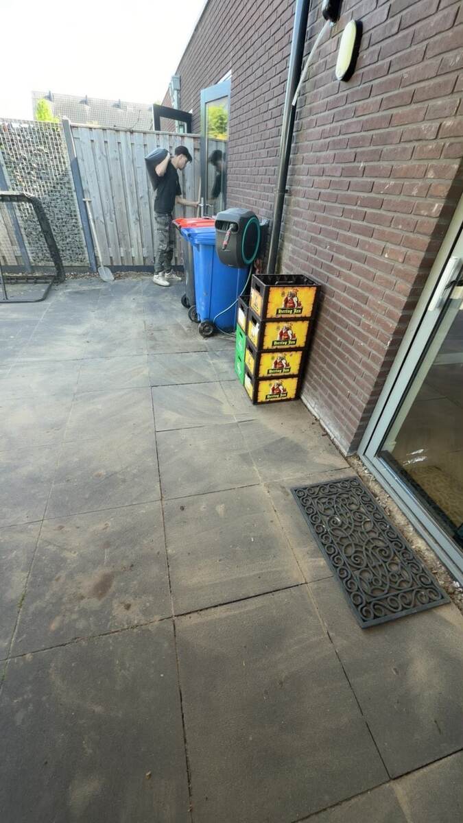 Werkplek op een betegeld terras bij de regenpijp en hemelwaterafvoer van een woning
