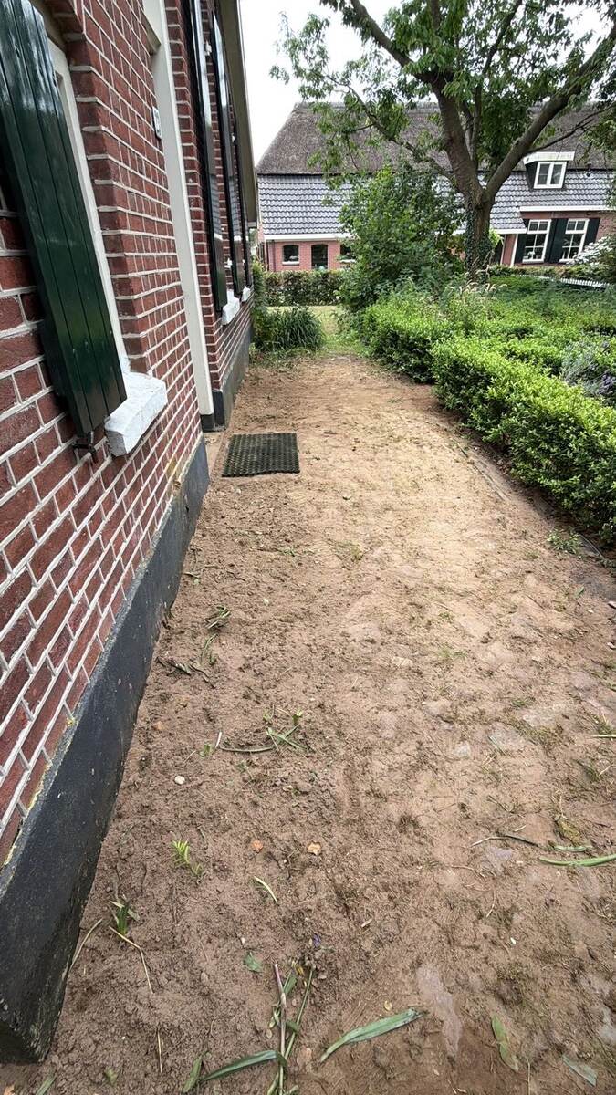 Straatkolk in een zandstrook langs een pand nadat de rioolleiding is aangepakt